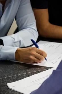 Gros plan d'une main écrivant sur un document au stylo.