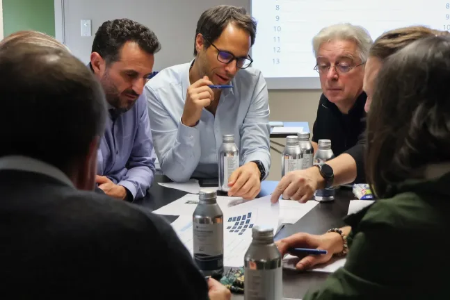 Équipe AMJ Groupe en réunion analysant des documents pour prendre des décisions projet